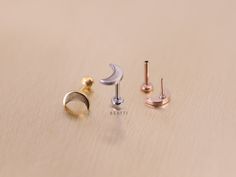 three pairs of earrings sitting on top of a wooden table with one earring in the shape of a crescent