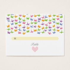 a place card with colorful origami cranes on it and a heart in the middle