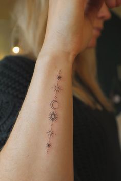 a woman with a small tattoo on her arm and the sun, moon and stars