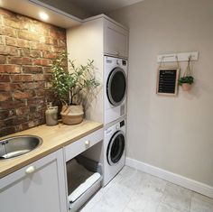 a washer and dryer in a small room next to a counter with plants on it