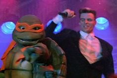 two men dressed up as teenage mutant and ninja turtle in front of a stage backdrop