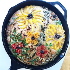 a skillet filled with food on top of a white counter next to a wooden spoon