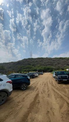 there are many cars parked on the dirt road