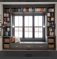 a window seat in front of a bookshelf filled with lots of bookcases