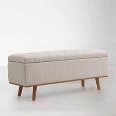 an upholstered bench with wooden legs and a beige fabric cover on the back