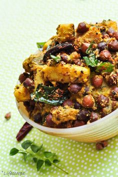 a wooden bowl filled with beans and other food on top of a green tablecloth