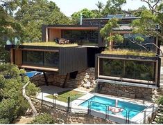 an aerial view of a house with a swimming pool in the foreground and trees surrounding it