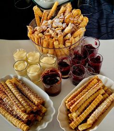 a table topped with plates and bowls filled with food next to glasses full of liquid