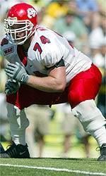 a football player squatting on the field with his hands in his pockets as he prepares to run