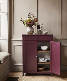 a vase with flowers sitting on top of a cabinet