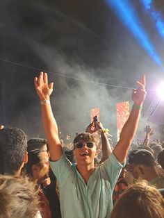 a woman with her hands up in the air at a music festival, surrounded by other people