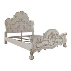 a white bed with ornate carvings on the headboard and foot board, against a white background