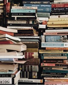 a pile of books stacked on top of each other in front of a wall full of them