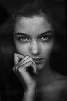 a black and white photo of a woman with freckles on her face looking at the camera