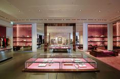 the inside of a clothing store with pink lighting and display cases filled with necklaces