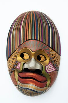 a colorful mask hanging from the side of a wall on a white background with stripes