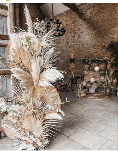 an arrangement of dried plants in a room with brick walls