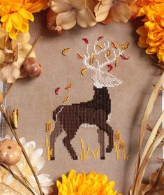 a cross - stitch pattern with flowers surrounding it and a deer on the back ground