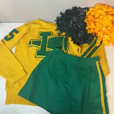 two green and yellow cheerleader uniforms with flowers on the floor in front of them