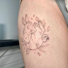 a woman's thigh with a tattoo of two rabbits sitting on top of each other