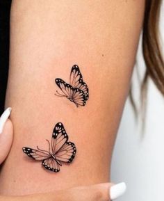 two butterflies tattoo on the side of a woman's right arm, one is black and white