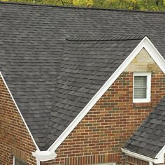 a brick house with a black roof and white trim