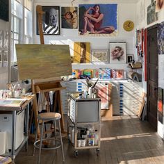 an artist's studio with lots of paintings on the wall