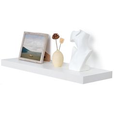 there is a white vase with flowers on the shelf next to an empty picture frame