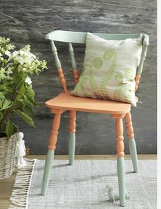 a chair with a pillow on it next to a potted plant and a rug