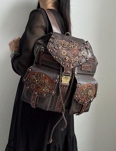 Steampunk womens leather backpack is my author's manual work! Materials: genuine brown leather, metal hardware. Sizes: 12 inches (width), 14 inches (height), 8 inches (depth). There is a beautiful decoration with metal hardware in Steampunk style on the front side of this travel backpack. The leather backpack purse for women has one handle, two big pockets on the front side and two adjustable straps. There are 2 small pockets, 1 big pocket, 1 zipped pocket and a key carabine inside this leather bag for women. My travel bag and other leather goods may be great birthday gifts, bridesmaid gifts for her or back to school teacher gifts! Please, look through my shop to see other gifts for women: leather journals, womens leather wallets, womens leather bracelets, etc. You may also order your own Luxury Vintage Leather Backpack With Multiple Compartments, Brown Leather Bags With Hardware, Steam Punk Backpack, Fantasy Leather Backpack, Gothic Brown Bag For Everyday Use, Elegant Leather Satchel Backpack For On-the-go, Bohemian Leather Backpack For Daily Use, Brown Leather Bags With Rivets, Gothic Brown Bag