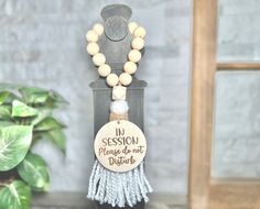 a wooden beaded necklace with a message on it sitting next to a potted plant