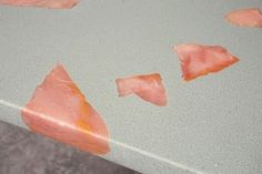 some pieces of meat sitting on top of a white table with brown spots around them