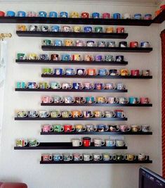 the coffee mugs are lined up on the wall above the computer desk in this living room