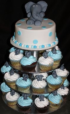 a three tiered cake with cupcakes and an elephant on top