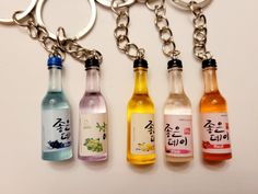 four different kinds of alcohol bottles on a keychain with chinese characters written in the bottle