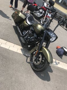 two motorcycles parked next to each other on the side of the road with people walking by