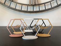 three different colored hexagonal coasters sitting on top of a table next to a clock