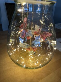 a glass jar filled with paper butterflies on top of a wooden table