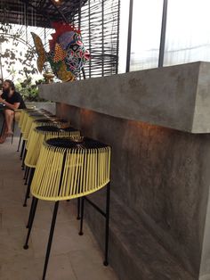 yellow chairs are lined up against the wall in front of people sitting at their tables