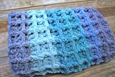 a blue and purple crocheted dishcloth on a wooden surface