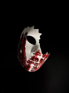 a white mask with red paint splattered on it's face in the dark