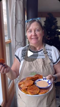 a woman in an apron holding a plate of food