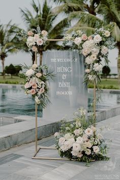 an outdoor ceremony setup with flowers and greenery on the ground next to a pool