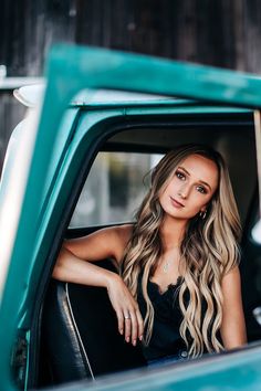 a beautiful young woman sitting in the back of a green pick up truck with long hair