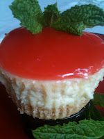 a piece of cheesecake on a red plate with mint leaves around it and a green garnish