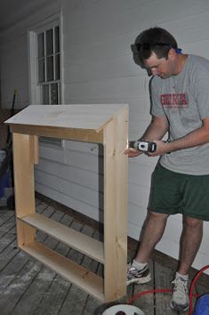 a man is sanding up some wood on the porch with an electric driller