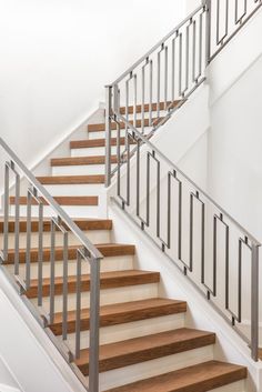 a staircase with wooden handrails and metal railing on the bottom, along with white walls