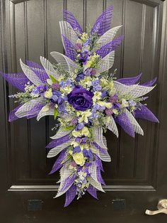 a purple and white floral arrangement in front of a door