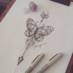 two pens sitting on top of a piece of paper next to some rocks and a butterfly