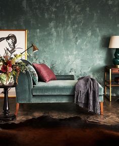 a living room with green walls and a blue couch in the corner, surrounded by two lamps